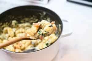 gnocchi in a dutch oven pan scooped with a wooden spoon