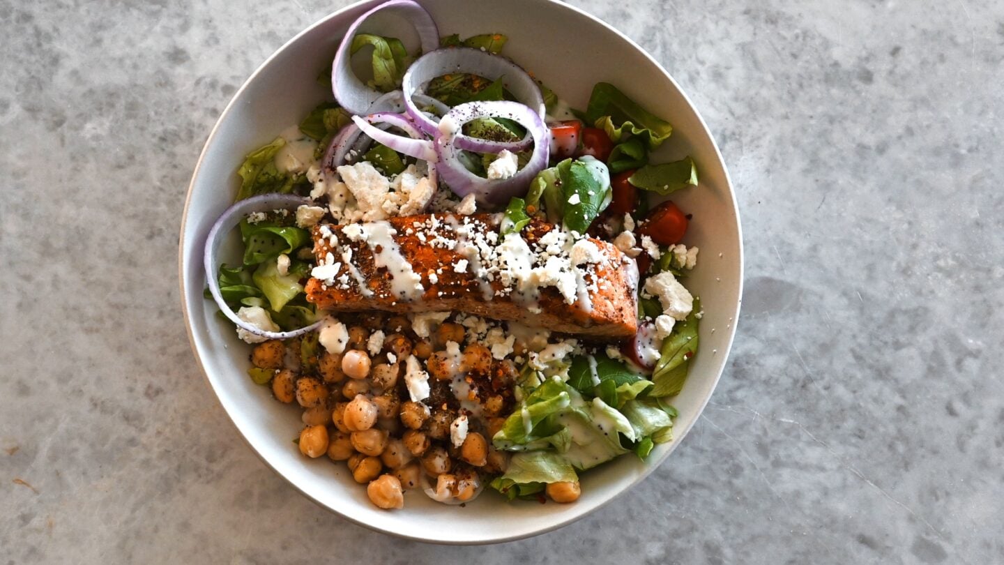 Greek-Style Salad in bowl with salmon on top