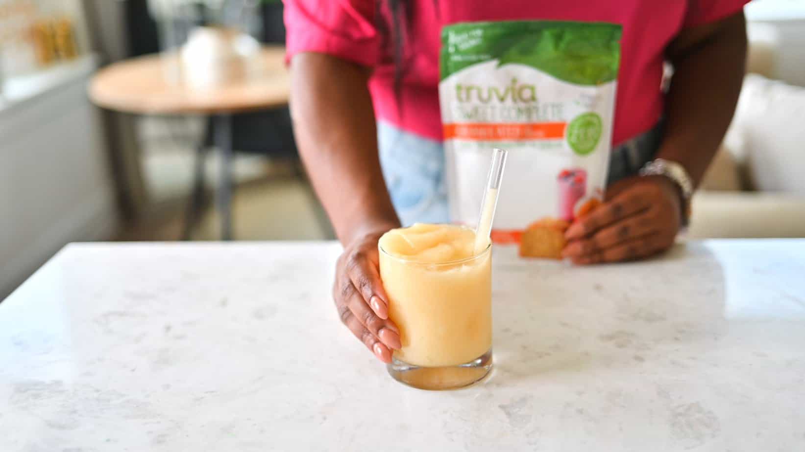 Saturn cocktail in mila's hands on a counter with Truvia Sweet Complete in a package behind.