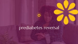 A woman sitting on a couch using a glucose monitor on her arm, with the words 'prediabetes reversal' overlaid, symbolizing proactive health monitoring and hope for reversing prediabetes.