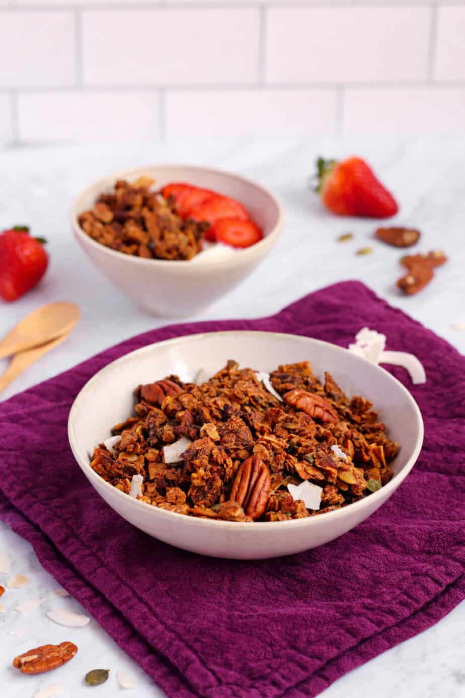 Lower carb oat granola on a purple napkin with strawberries, and a little bit of yogurt in the background.