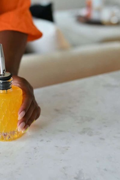 glass bitters bottle with person holding simple syrup